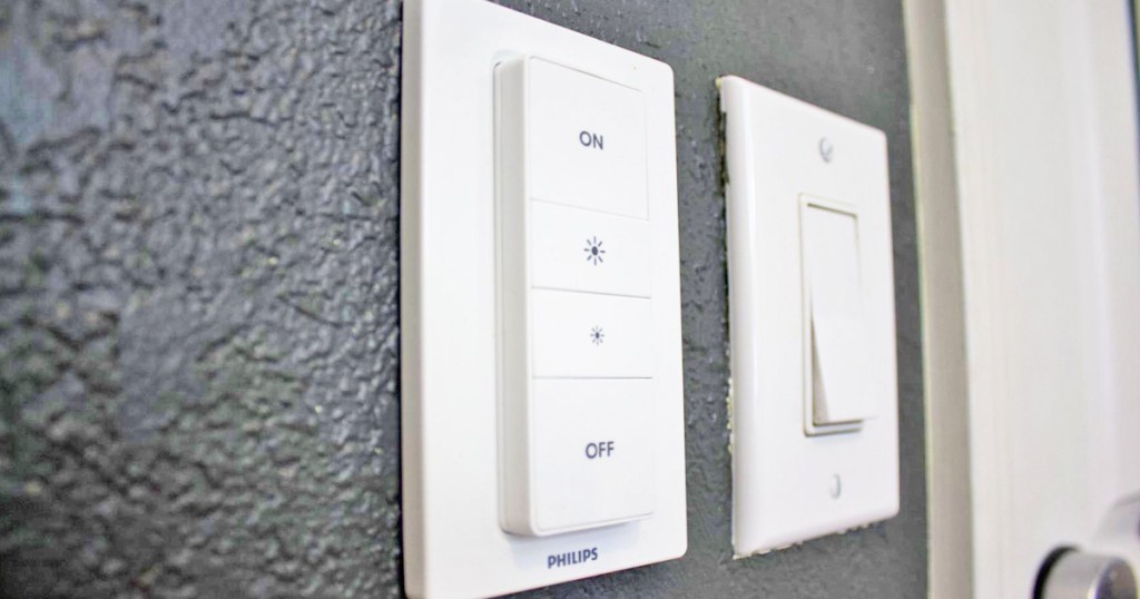 philips hue light dimmer switch on black wall next to standard light switch