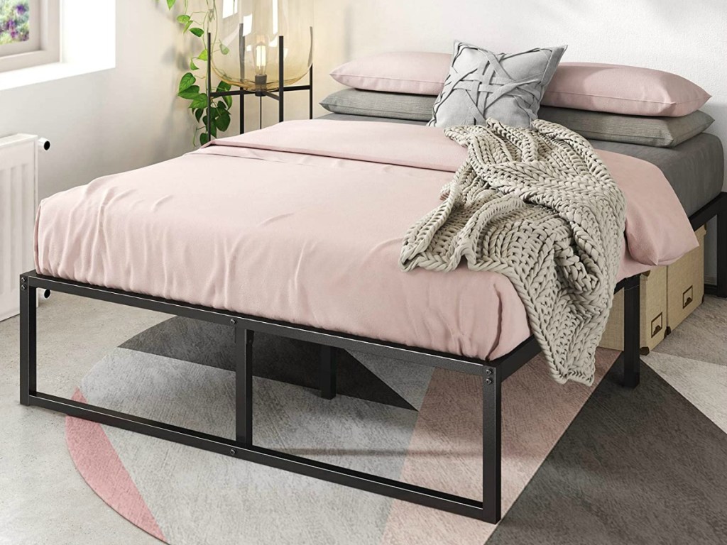 Metal platform bed made up with pink sheets