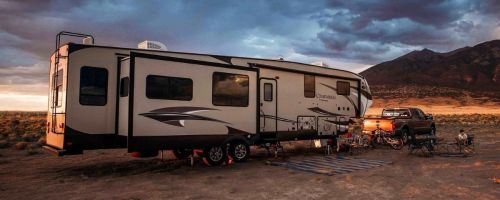 camper on sand with a sunrise in the background