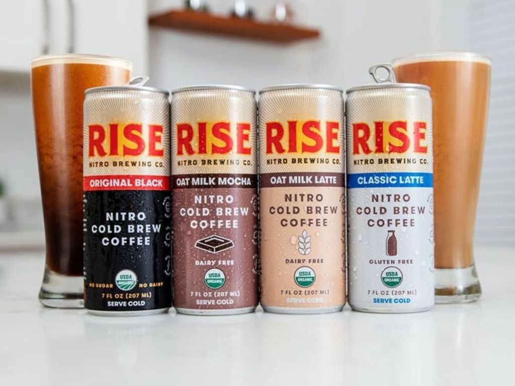 four cans of cold brew coffee in front of pilsner glasses filled with cold brew coffee