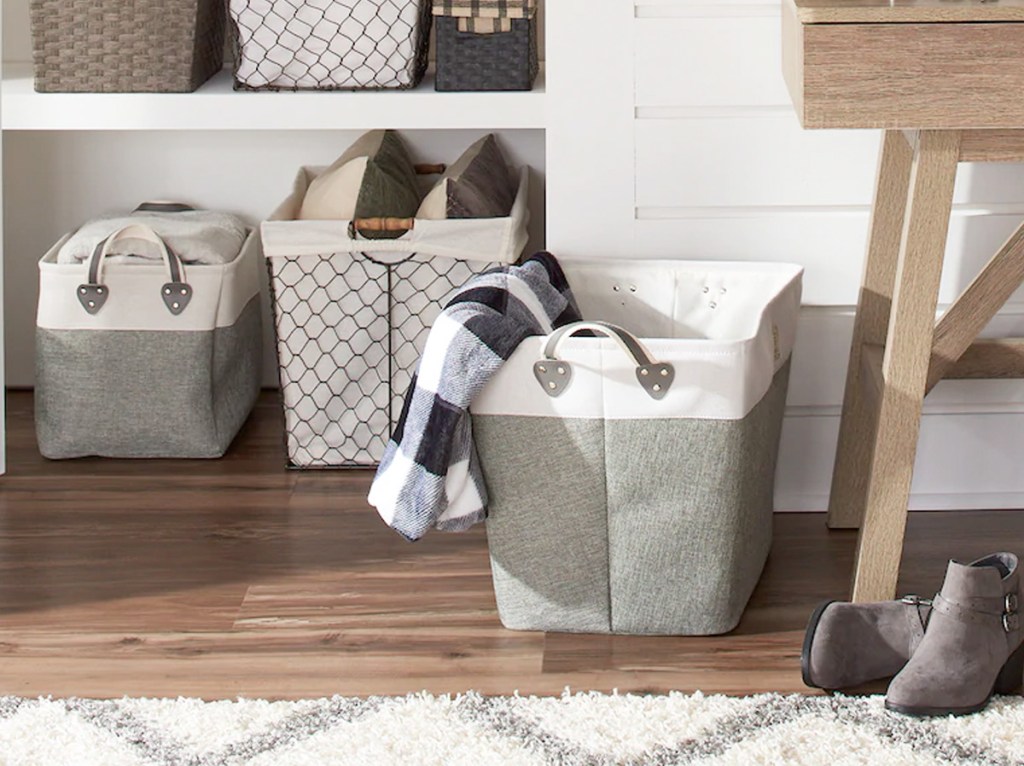 large grey and white fabric storage bin on floor next to built-in shleves full of other storage bins