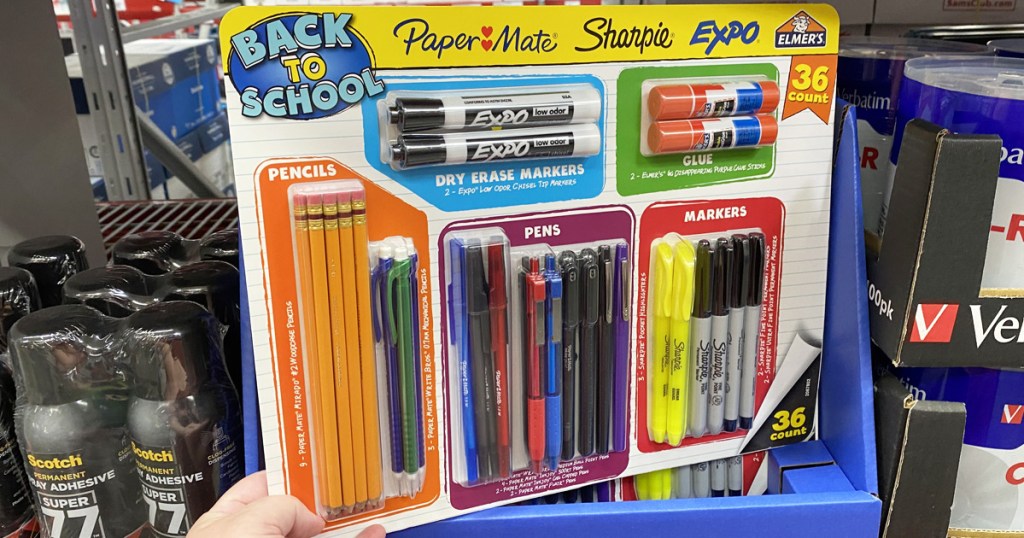 person holding up 36-piece back to school kit with an assortment of pens, pencils, markers, and glue included