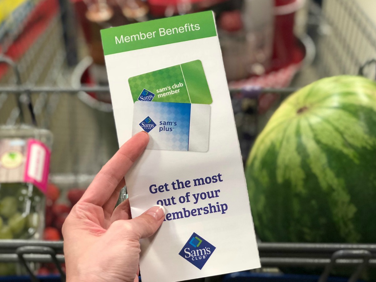 Hand holding a pamphlet for a Sam's Club Membership, in front of a shopping cart