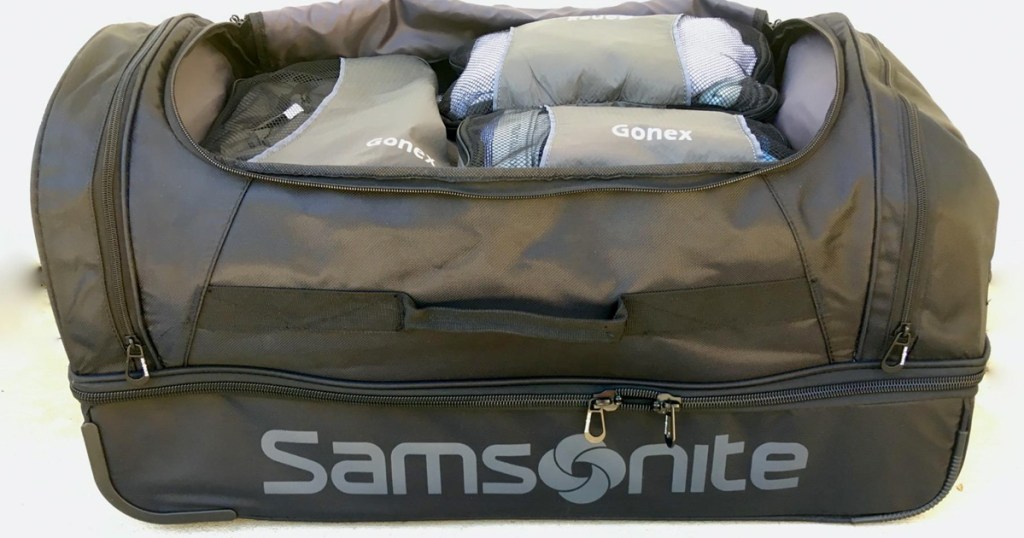 grey and black duffle bag that says samsonite on the side, opened and filled with clothing