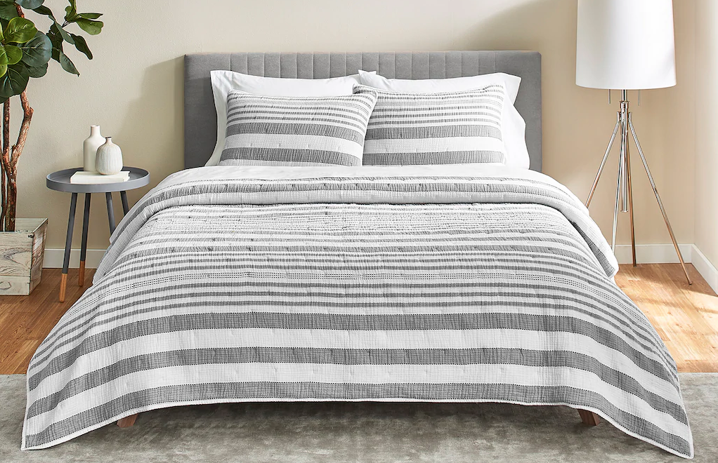 striped comforter on a bed with two pillows