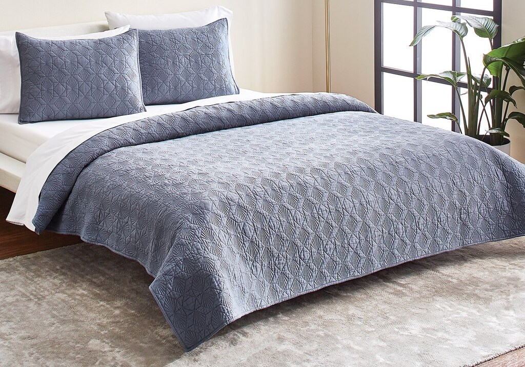 bed with diamond quilt on it and white sheets