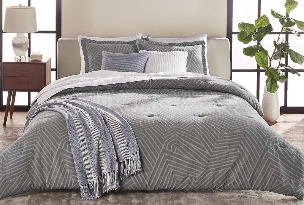 bed with grey comforter, pillows and a white pillow
