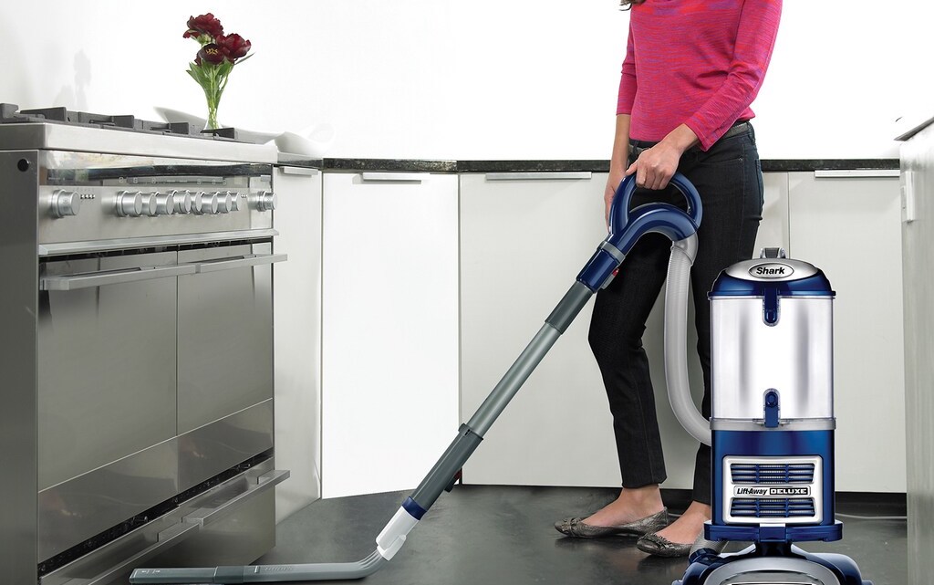 woman vacuuming under stove