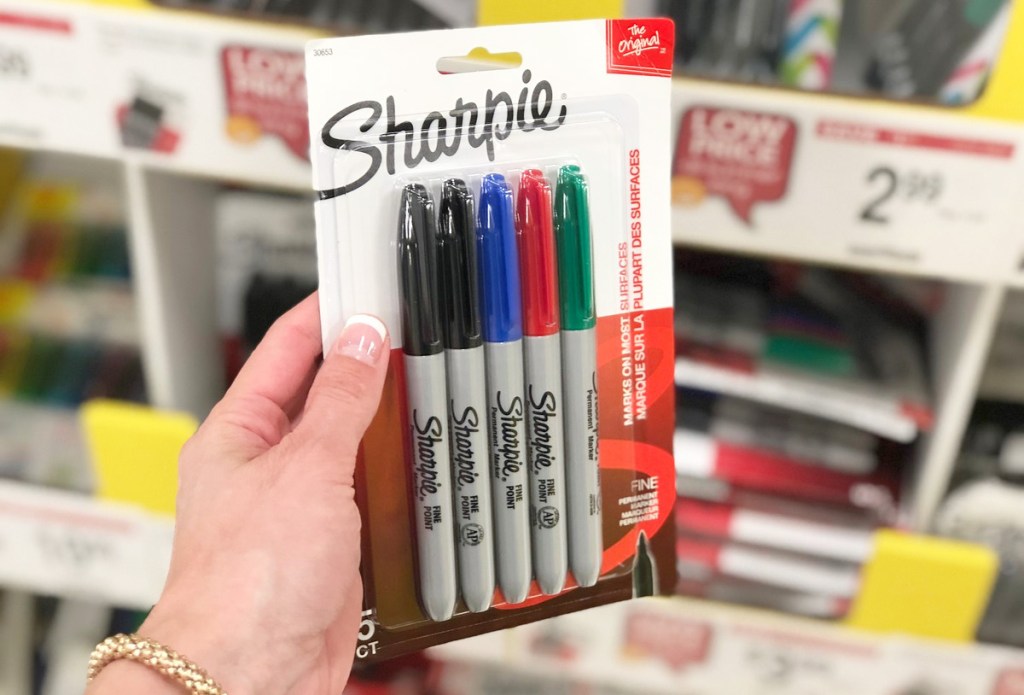 person holding a package of sharpie markers in black, blue, red, and green colors