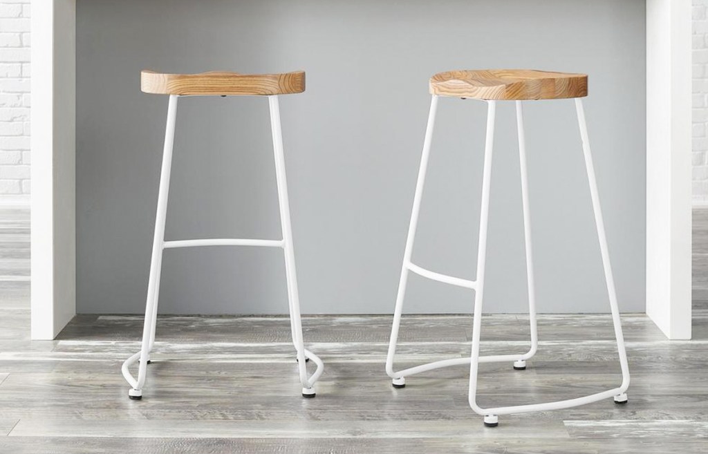 two white metal backless barstools with wooden seats
