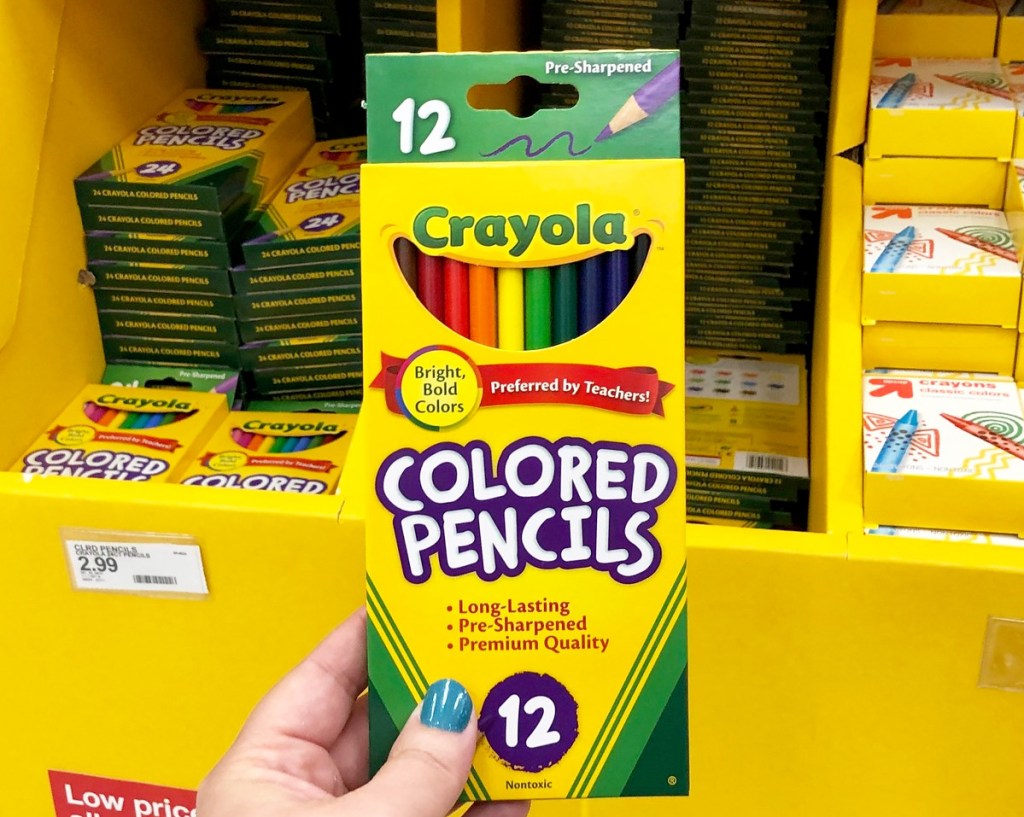 person holding a yellow and green box of crayola colored pencils