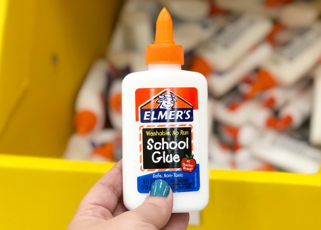 person holding a small bottle of elmer's liquid school glue with orange tip