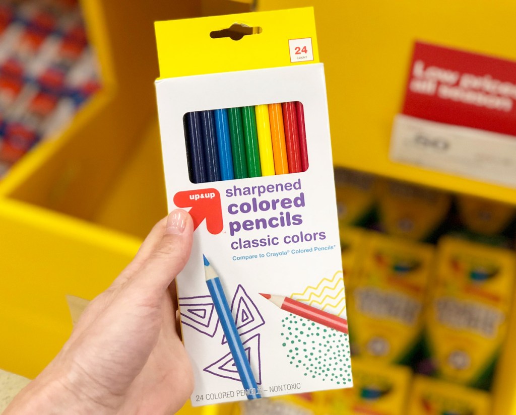 person holding a yellow and white 10-count package of colored pencils