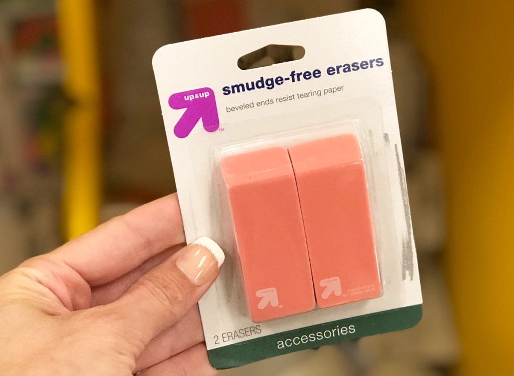person holding white package of two pink erasers