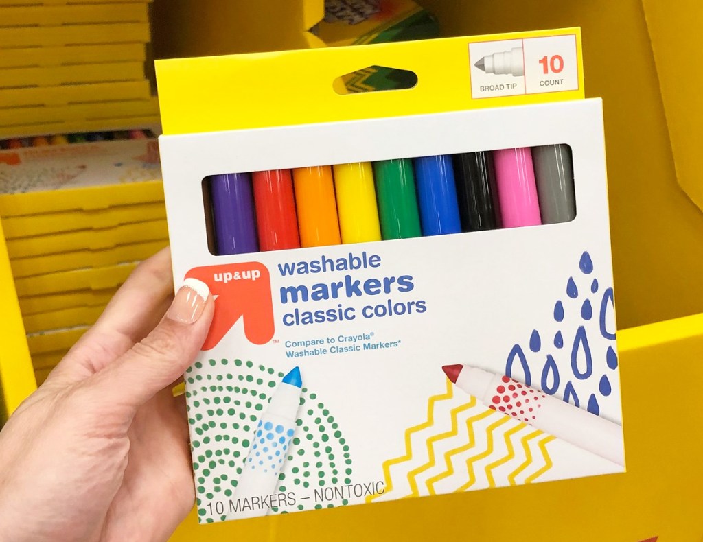 person holding a yellow and white package of assorted colored markers