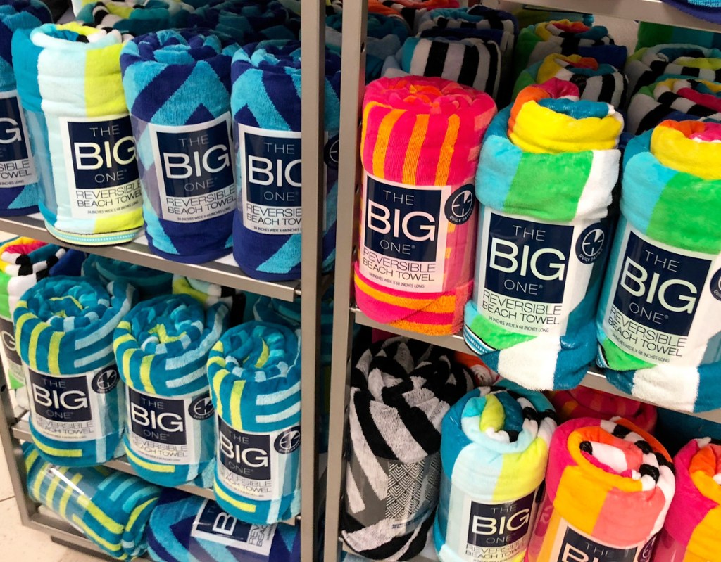 store display rack filled with rolled up beach towels in various prints
