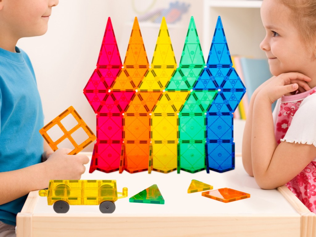 two kids playing with colorful toy building set on table