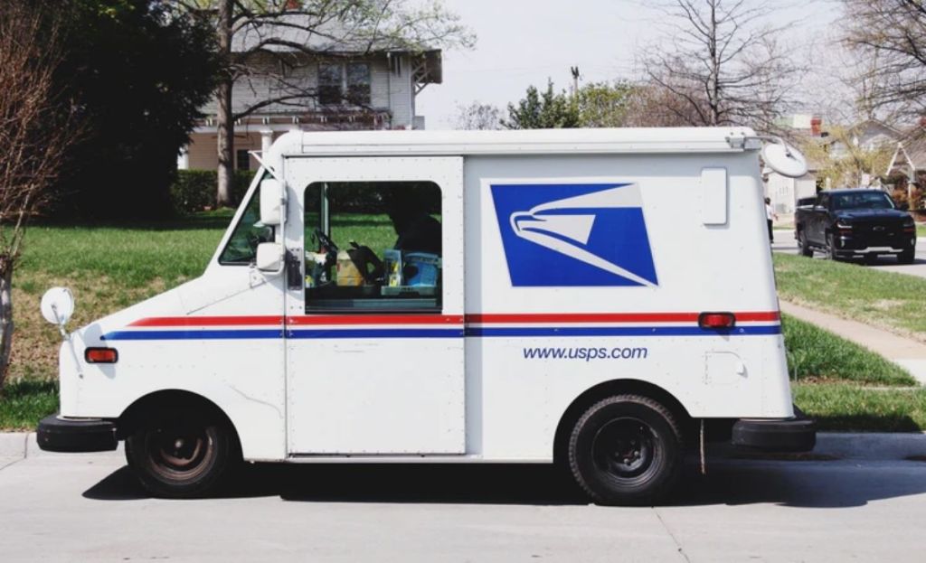 A USPS truck in front of a house