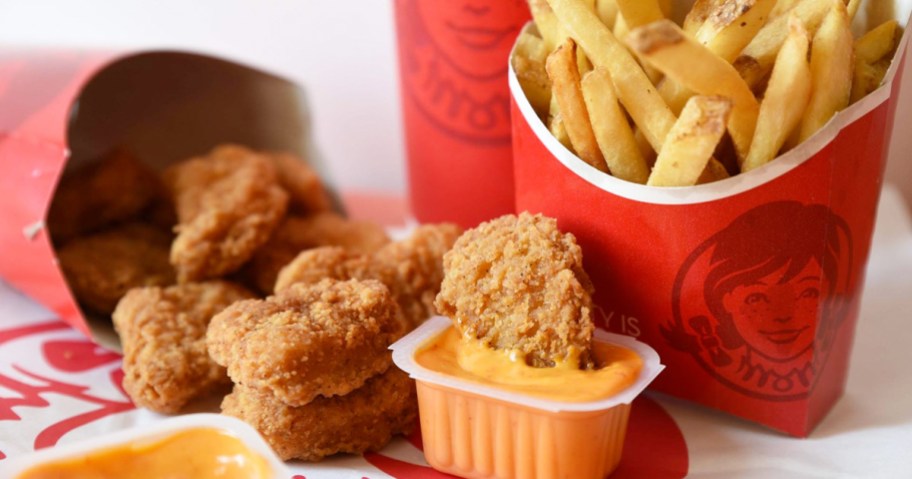 Wendy's chicken nuggets and fries with a nugget dipped into orange dipping sauce