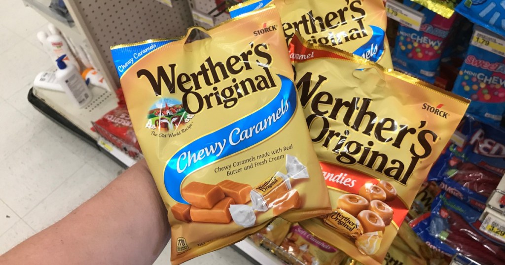 hand holding three bags of caramel candies in store