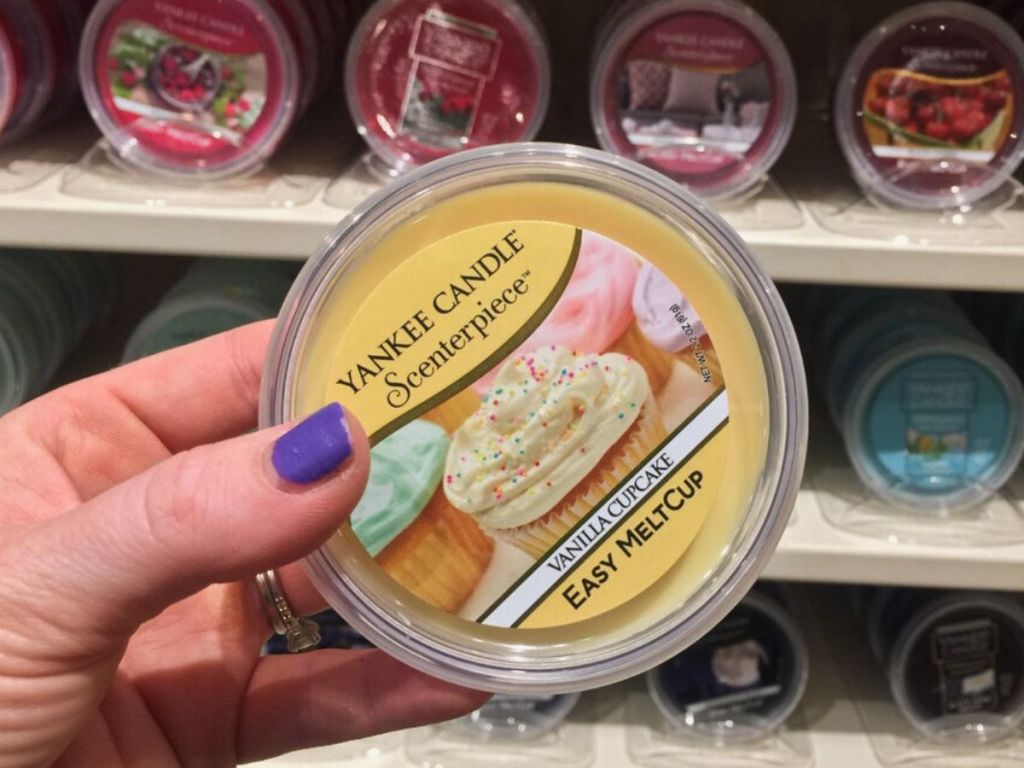 woman's hand holding a scented wax cup at store 
