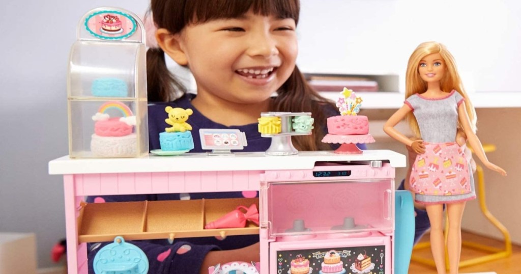 girl playing with blonde barbie doll and barbie cake decorator set