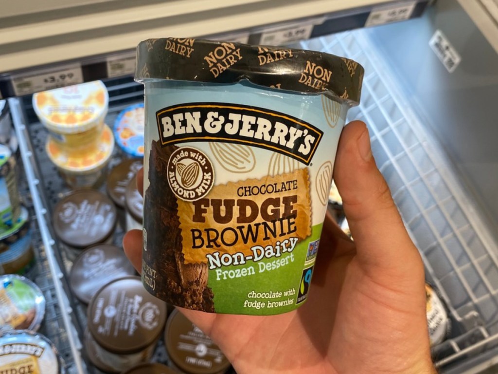 hand holding pint of ice cream by store freezer