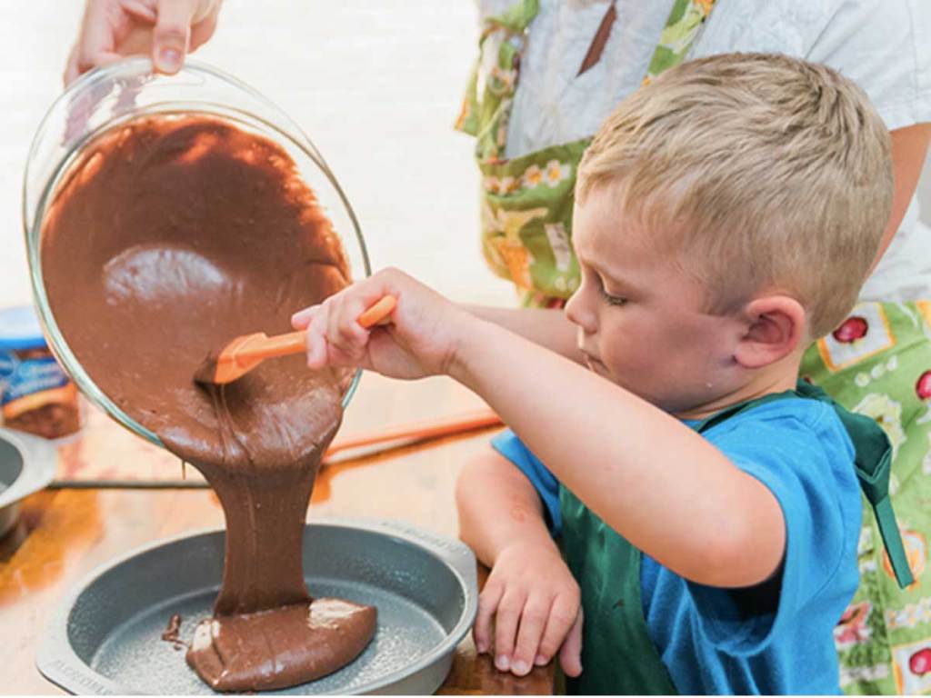 young boy pouring cake batter into pan