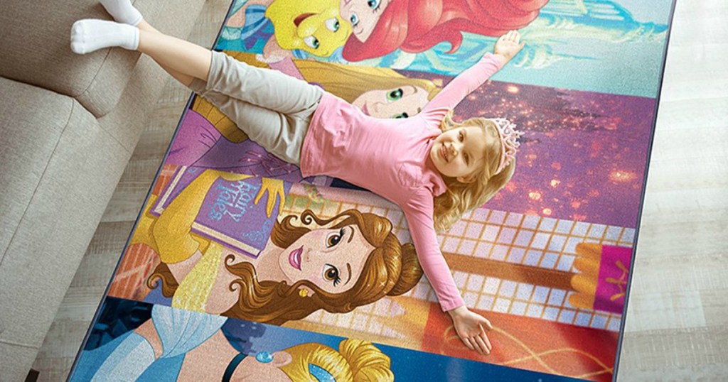 girl laying on a disney princess rug on the floor