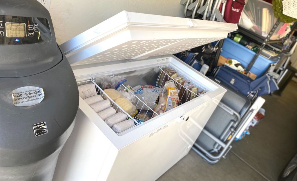 white chest freezer sitting in garage with lid open