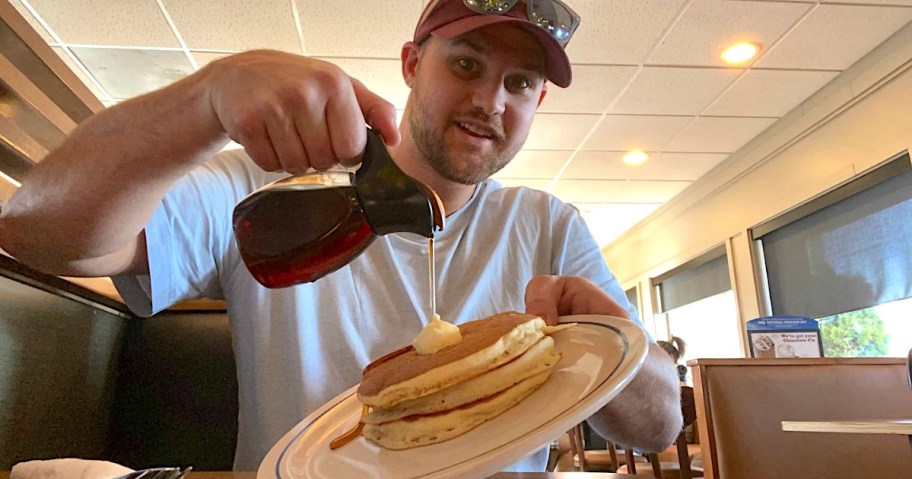 man pouring syrup on his pancakes