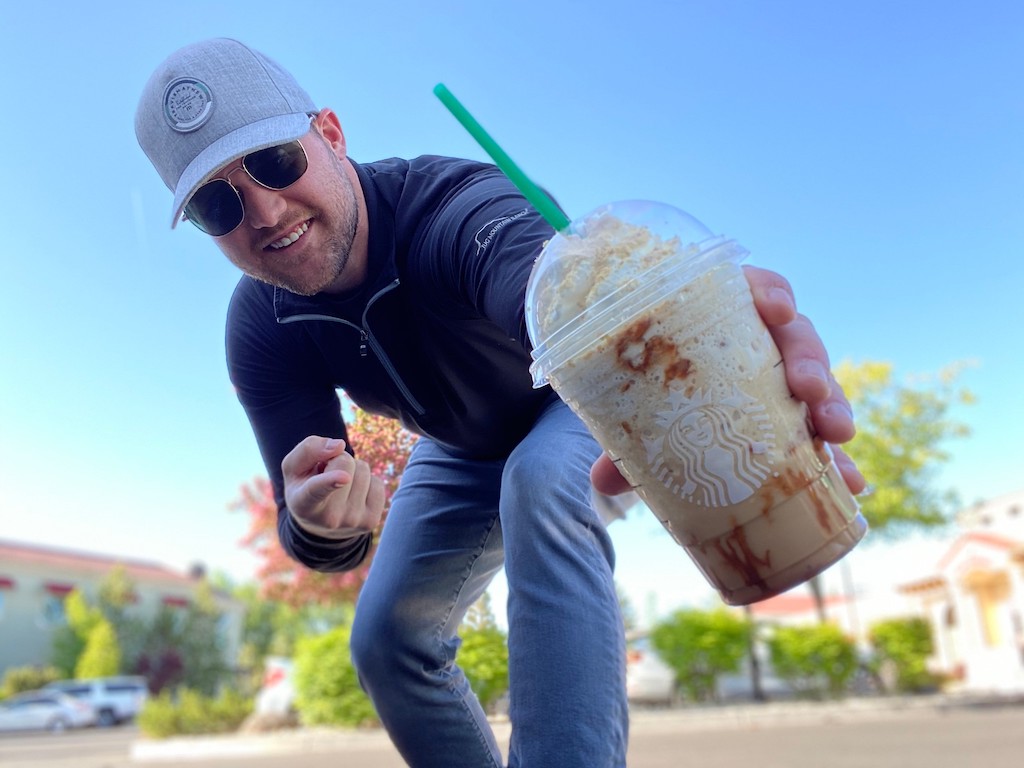 man holding Starbucks frapp blended beverage outside