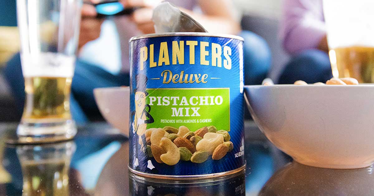 can of planters pistachio mix next to a bowl of nuts and half-filled beer glasses