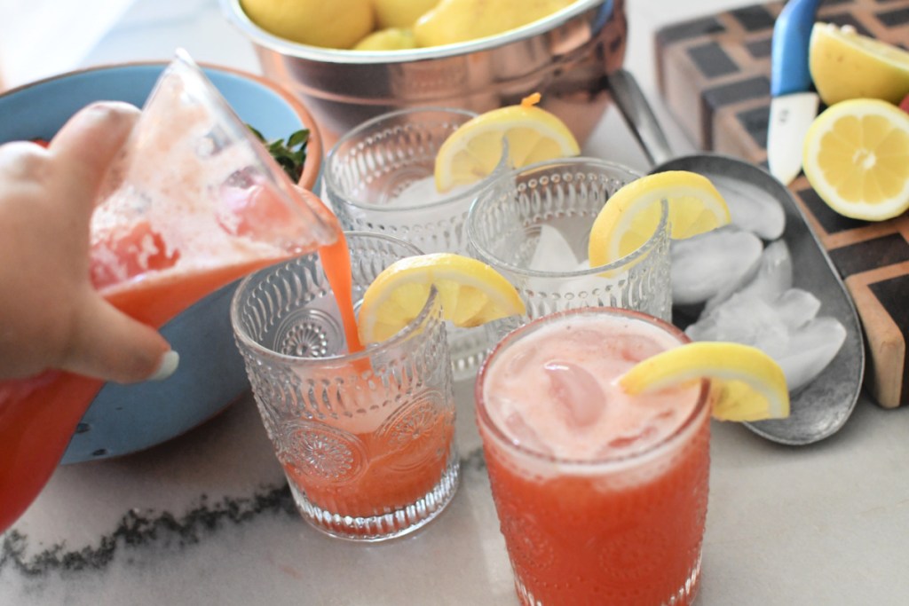 pouring strawberry lemonade into glasses