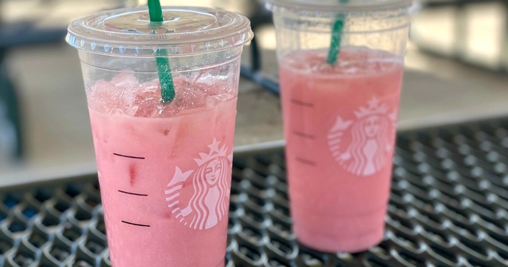 two Starbucks pink drinks with straws on outdoor metal table