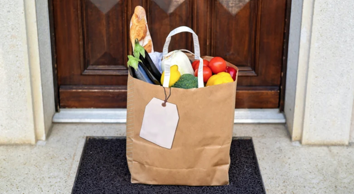 brown bag filled with food on front step door mat