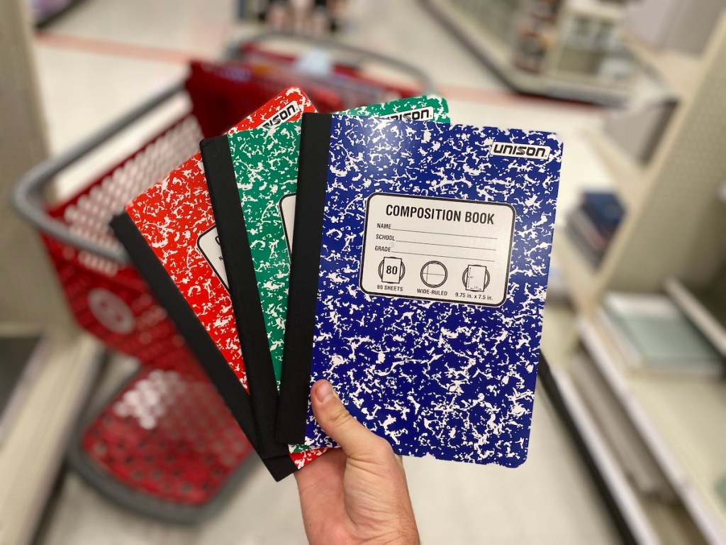 hand holding blue, red, and green colored unison composition books in target aisle