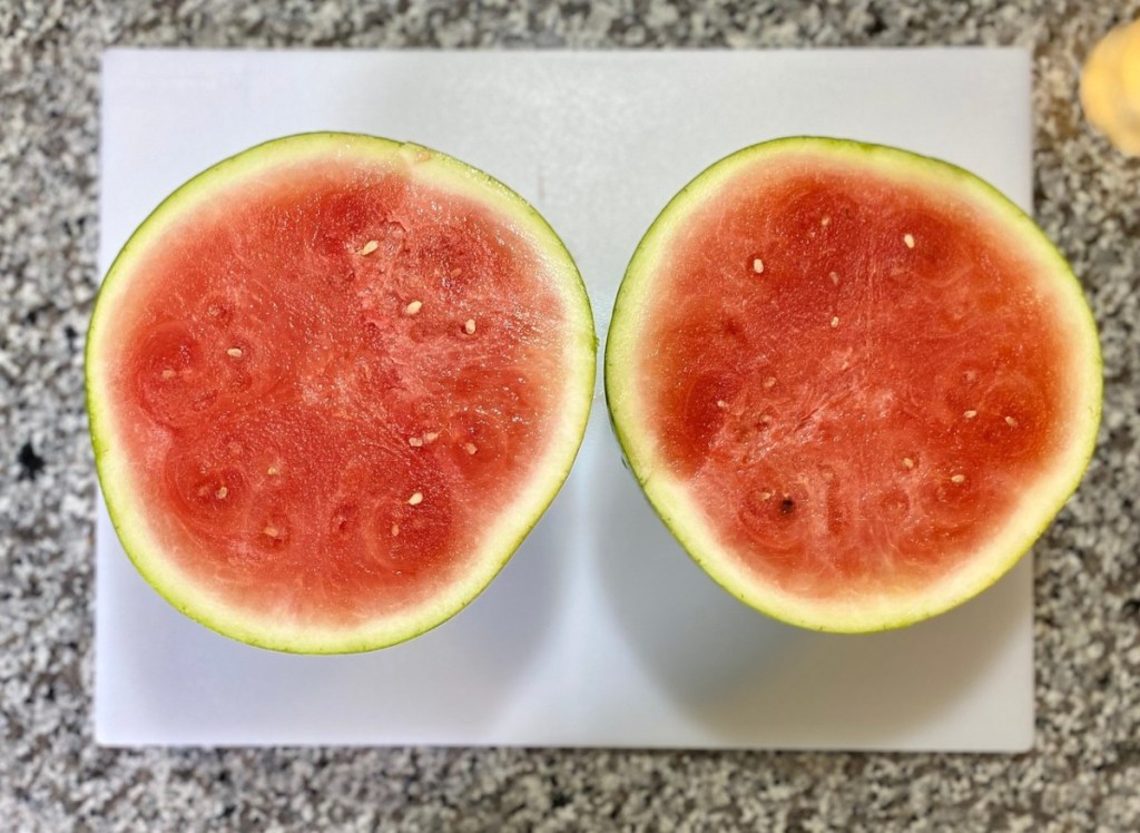 watermelon cut into two halves on cutting board