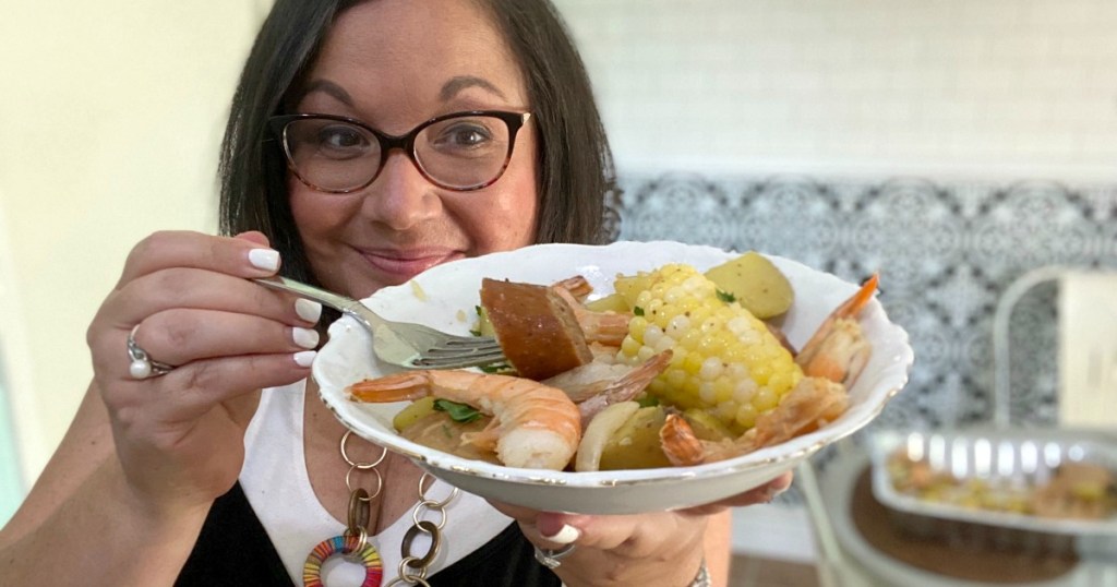 woman holding a plate of shrimp boil dinner