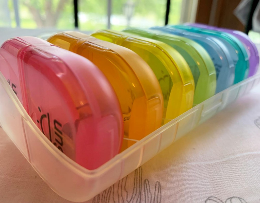 multi colored pill organizers inside white plastic container