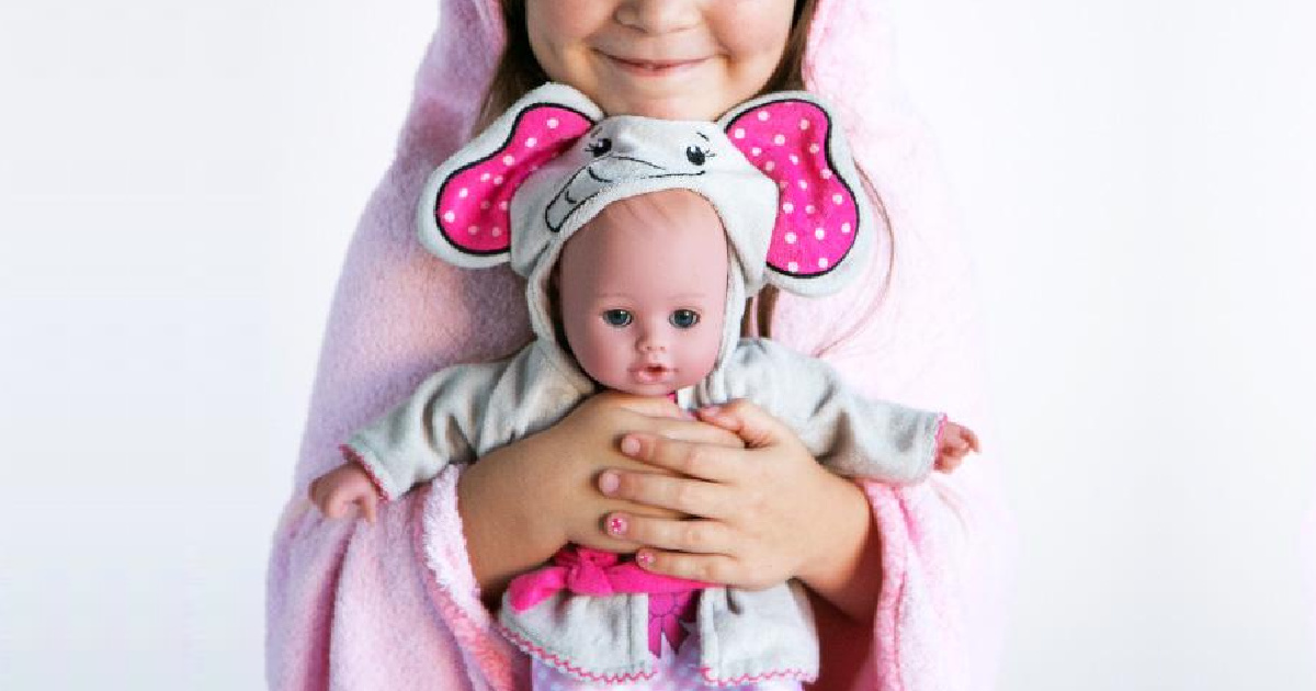girl in pink bathrobe holding baby doll in elephant themed robe