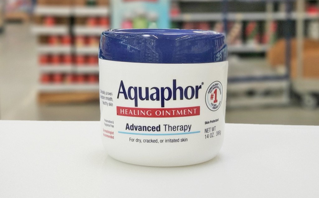 white and blue container of Aquaphor Healing Ointment on white table