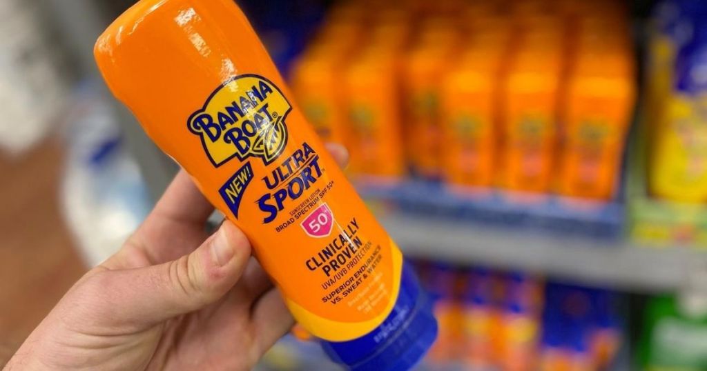 hand holding up bottle of sunscreen at store