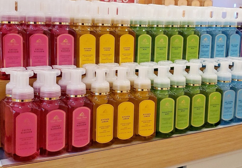 wood shelves lines with Bath & Body Works foaming hand soaps arranged in a rainbow order