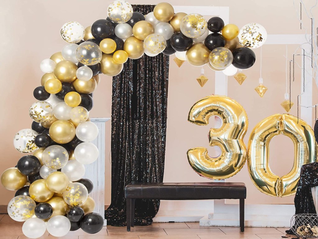 black, white, and gold balloon arch at indoor party
