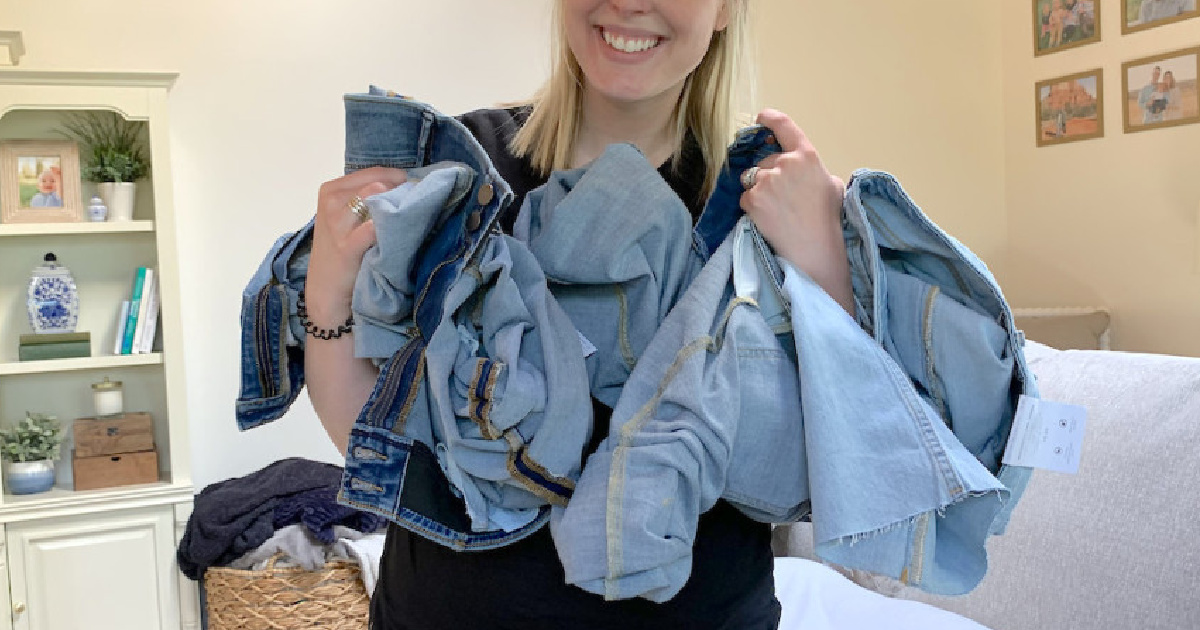 woman holding many pairs of jeans