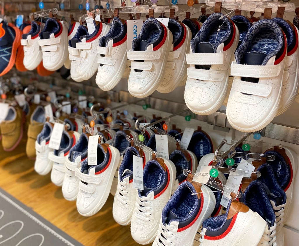 pairs of white toddler boys sneakers on hangers on Carter's store display