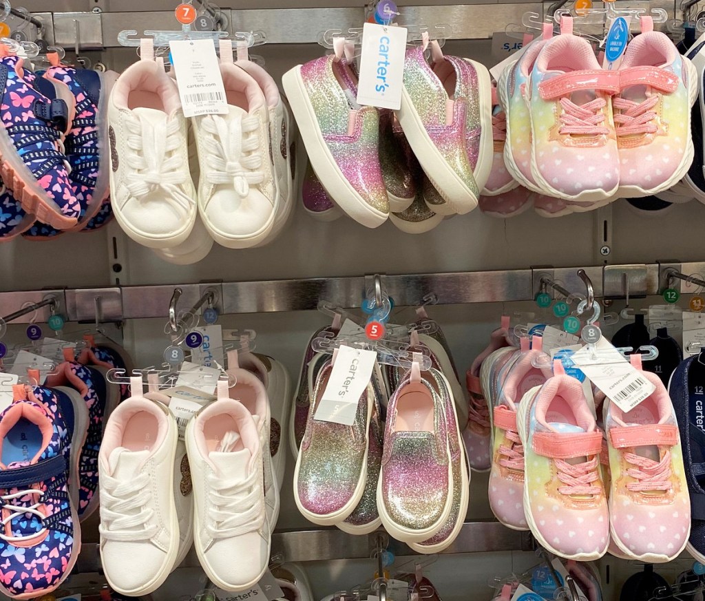 pairs of girls sneakers hanging on Carter's store display racks