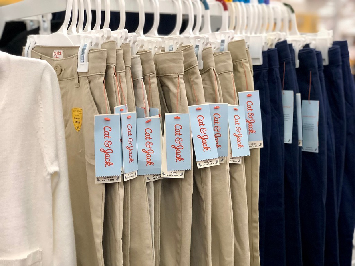 various colored kids uniform pants hanging on rack in store