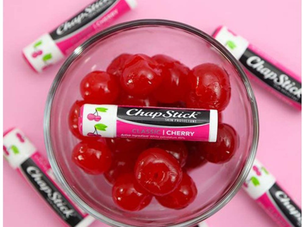 multiple cherry chapsticks on counter with a bowl of cherries
